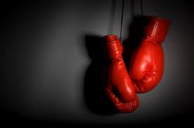 Boxing gloves hanging on a black background.