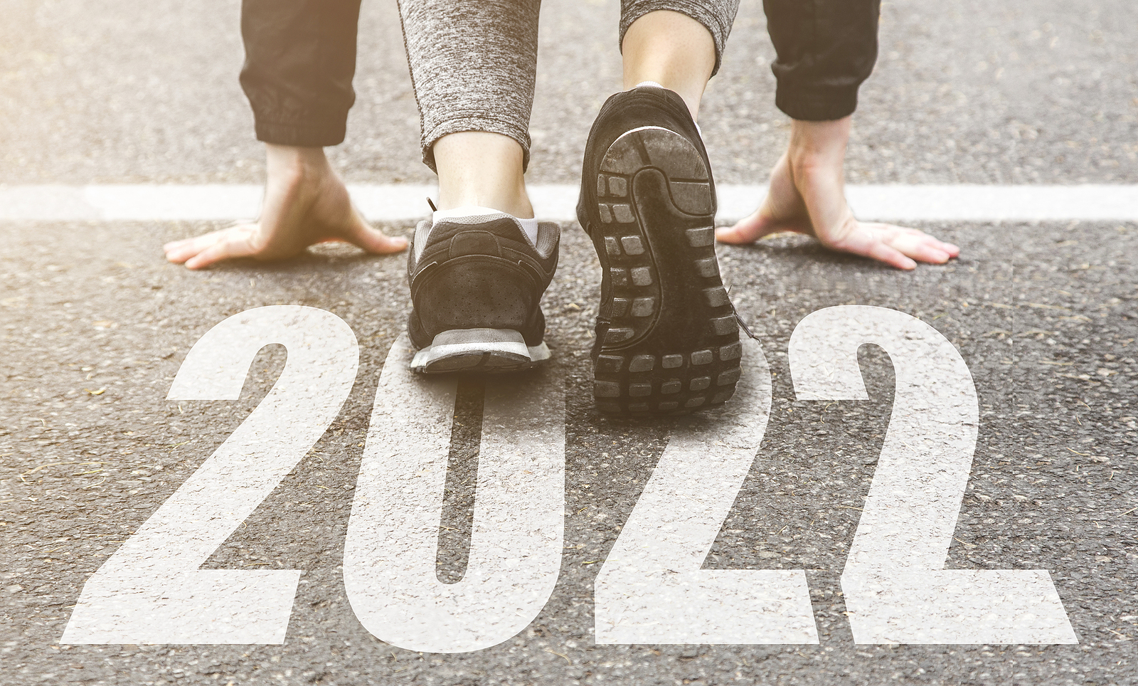 Woman in sneakers at starting line with 2022 on it.