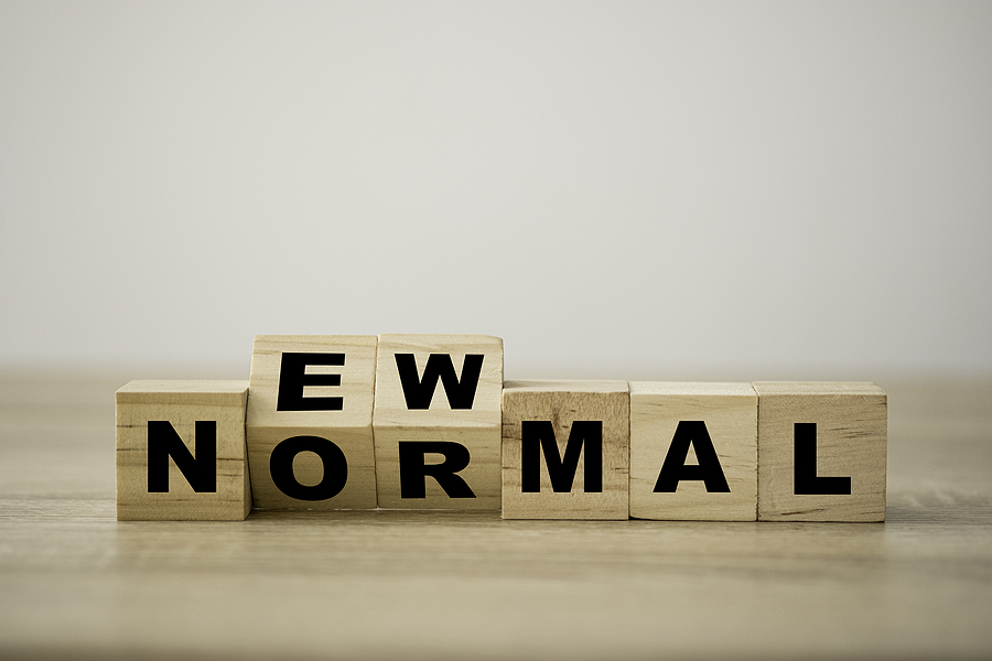 "New Normal" spelled out in wooden blocks on a plain background.