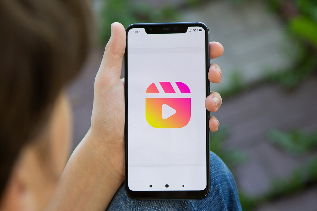 Person holding a smartphone with the Instagram Reels logo.