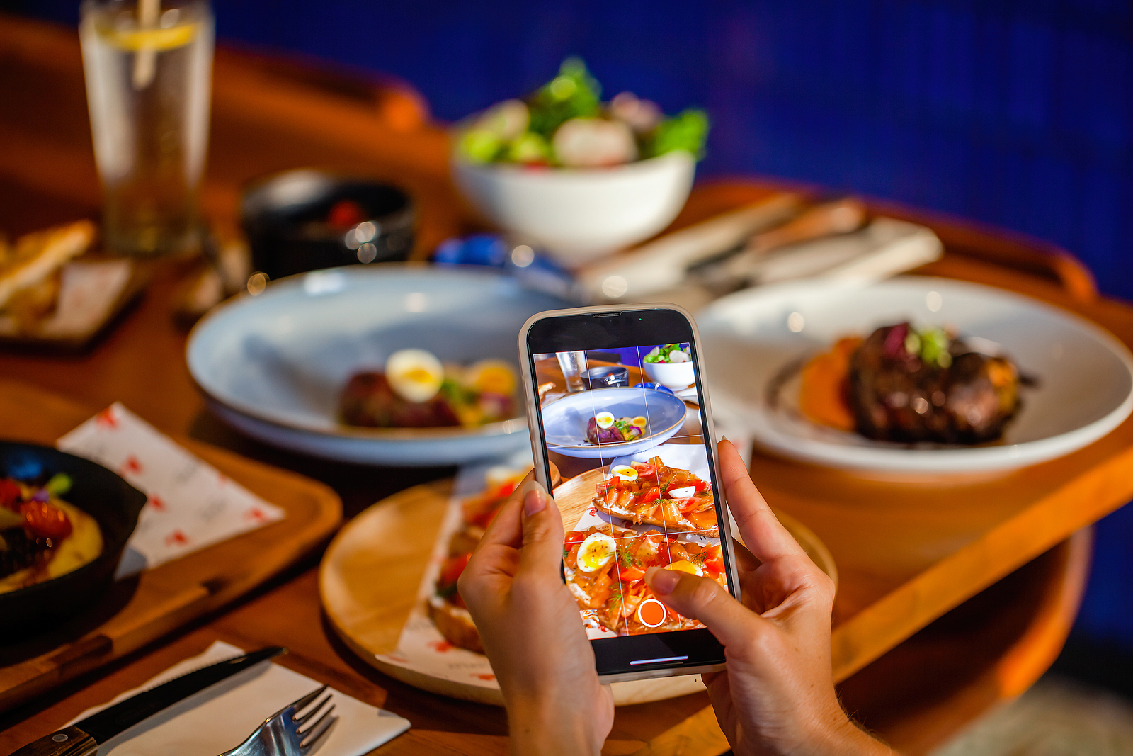 person photographing their food at a restaurant with phone.